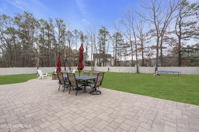 view of patio featuring a fenced backyard, a trampoline, and outdoor dining area