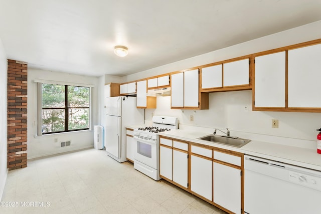 kitchen with white appliances, white cabinets, light countertops, under cabinet range hood, and a sink