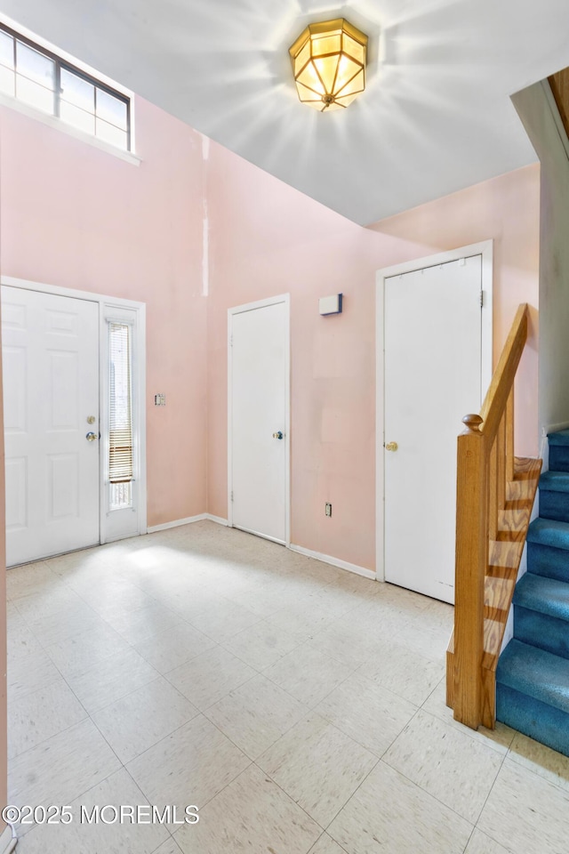 entryway featuring baseboards, a high ceiling, and stairway