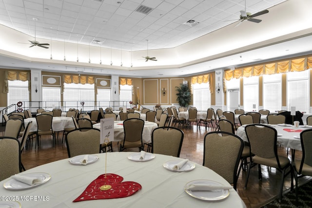 dining room featuring a ceiling fan, a tray ceiling, and visible vents