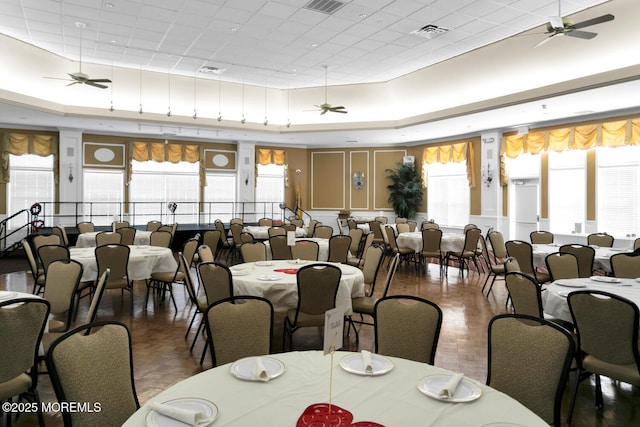 dining room with a raised ceiling, visible vents, and ceiling fan