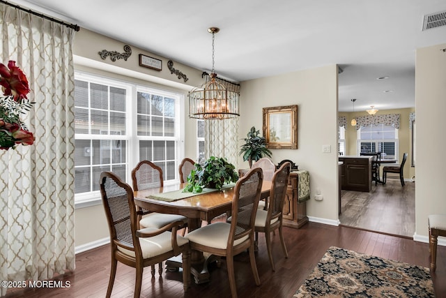 dining room with visible vents, dark wood finished floors, a notable chandelier, and baseboards