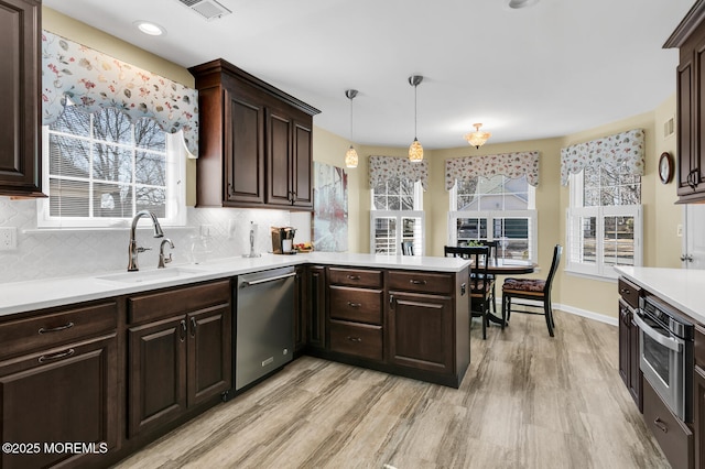 kitchen with dark brown cabinets, appliances with stainless steel finishes, light countertops, and backsplash