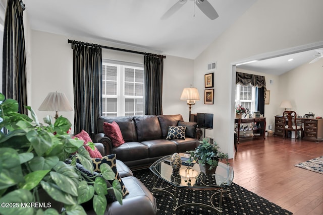 living area featuring vaulted ceiling, wood-type flooring, visible vents, and a ceiling fan