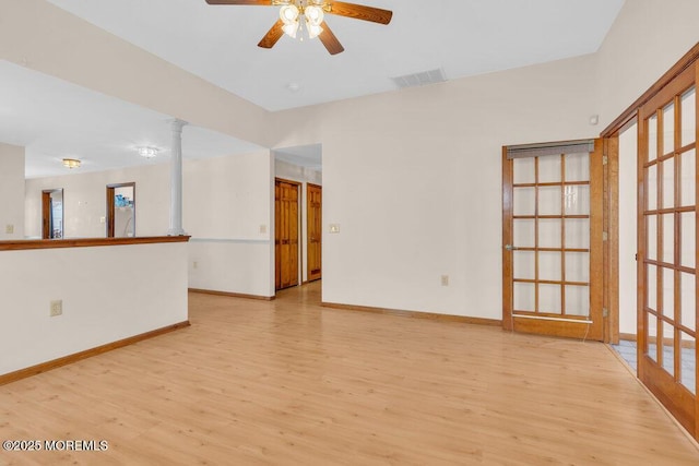 spare room with a ceiling fan, visible vents, baseboards, and wood finished floors