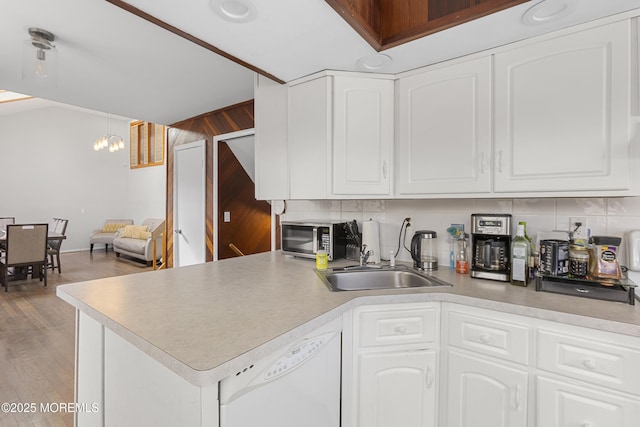 kitchen featuring dishwasher, a sink, white cabinetry, and decorative light fixtures