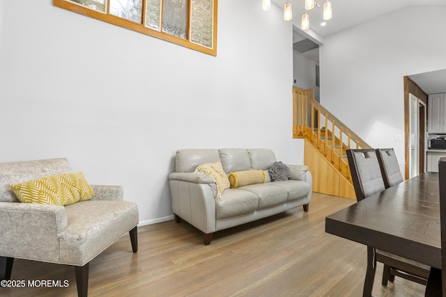 living area featuring lofted ceiling, baseboards, stairway, and wood finished floors