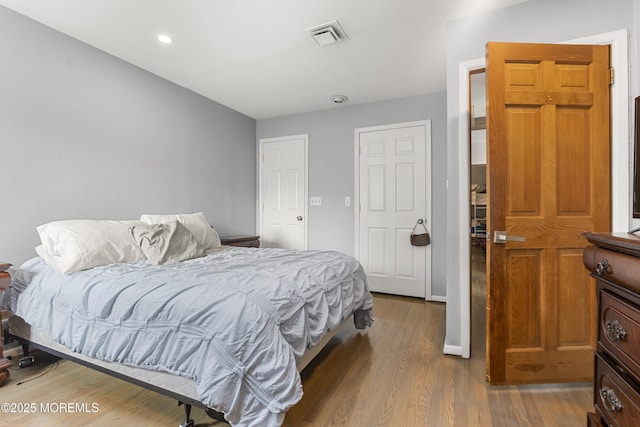 bedroom featuring baseboards, wood finished floors, visible vents, and recessed lighting