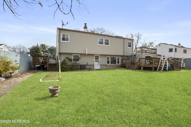 rear view of house featuring fence, stairs, a yard, a wooden deck, and a chimney