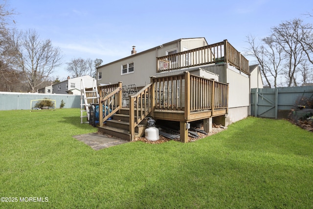 rear view of property with a fenced backyard, a gate, a deck, and a lawn