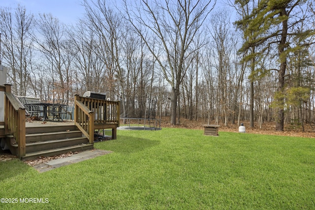 view of yard featuring a trampoline and a wooden deck