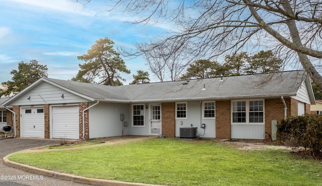 ranch-style house featuring an attached garage, aphalt driveway, a front lawn, and brick siding