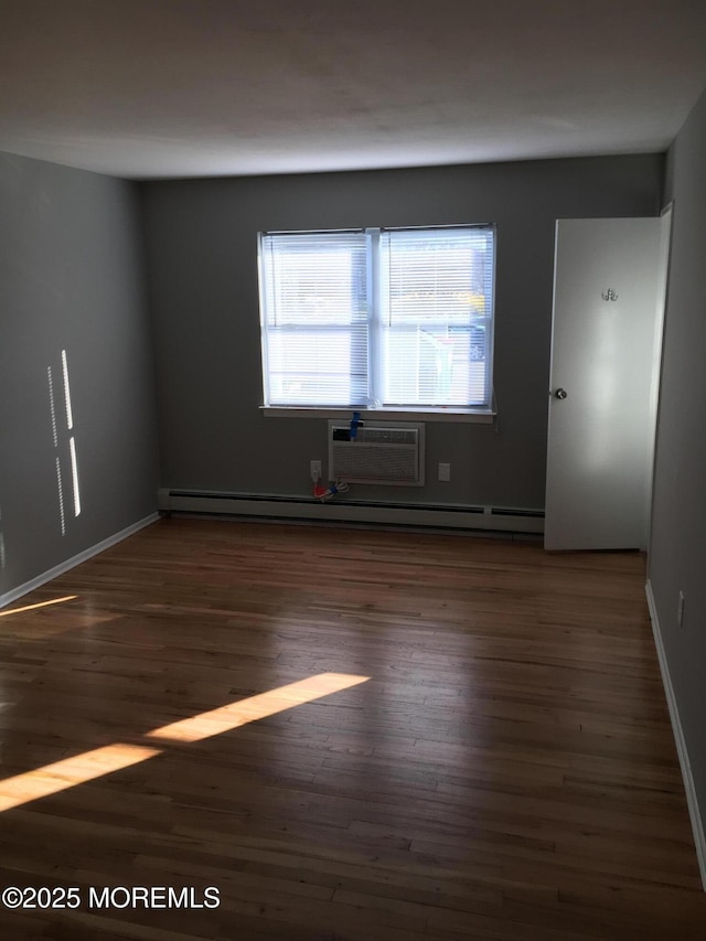 unfurnished room with a wall mounted AC, wood finished floors, and baseboards