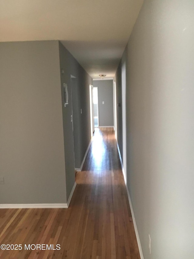 corridor featuring baseboards and dark wood finished floors