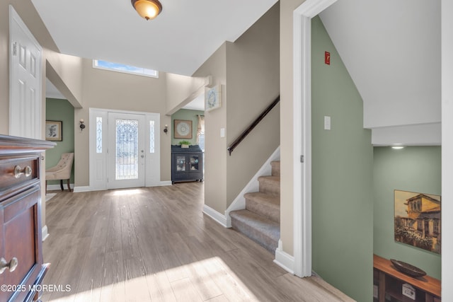 entrance foyer featuring light wood finished floors, baseboards, and stairway