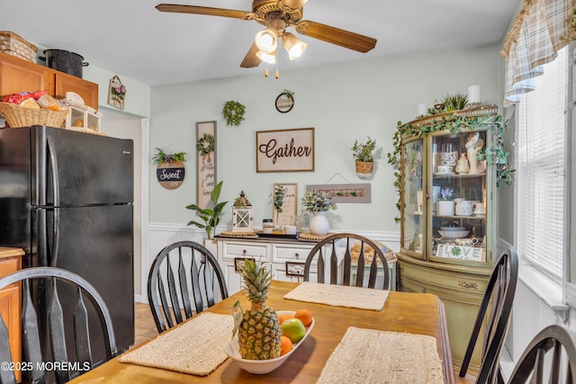 dining room with a ceiling fan and wainscoting