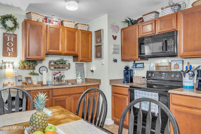 kitchen with black appliances, a sink, light countertops, and brown cabinets