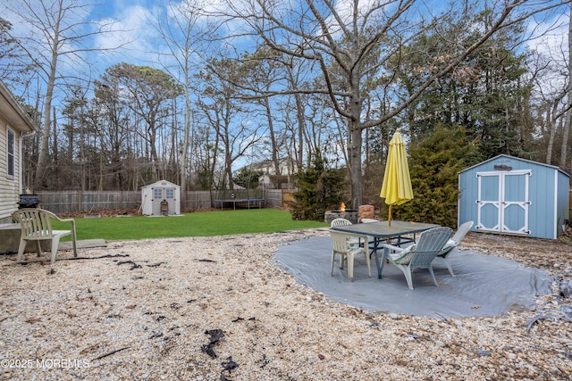 view of yard with a trampoline, a storage shed, a patio area, a fenced backyard, and an outdoor structure
