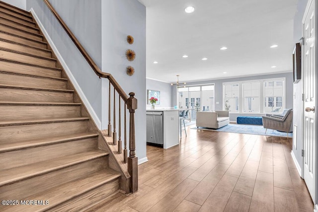 stairway with baseboards, wood finished floors, and recessed lighting