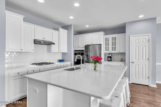 kitchen featuring appliances with stainless steel finishes, white cabinetry, a sink, and under cabinet range hood