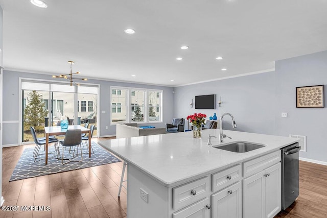 kitchen with a wealth of natural light, a center island with sink, a sink, and wood finished floors