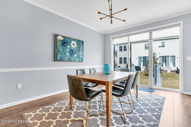 dining space with a chandelier, ornamental molding, wood finished floors, and baseboards