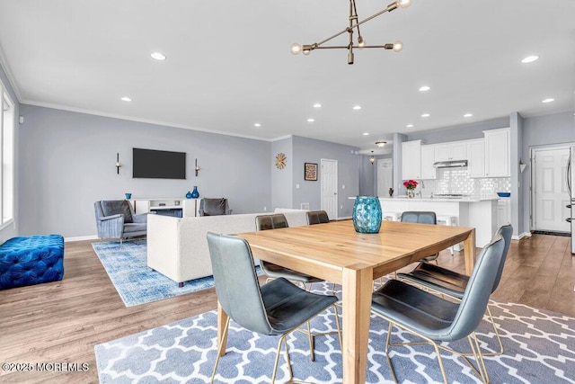 dining area featuring a notable chandelier, crown molding, recessed lighting, wood finished floors, and baseboards