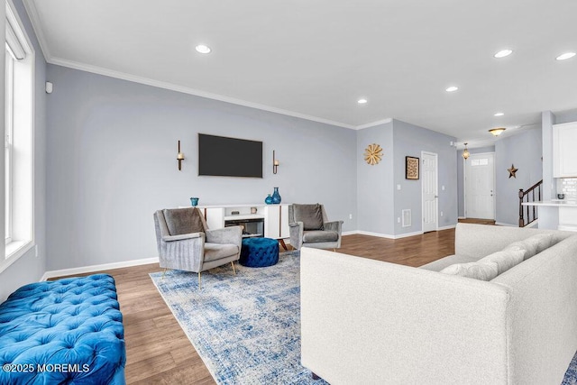 living area with stairs, recessed lighting, wood finished floors, and crown molding