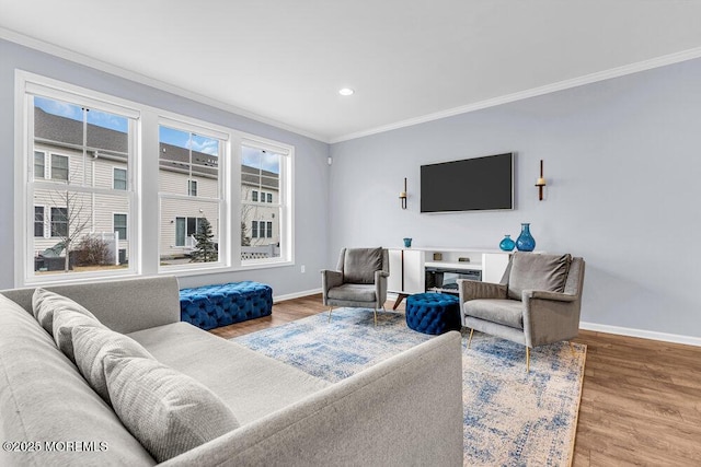 living area with baseboards, a glass covered fireplace, crown molding, and wood finished floors