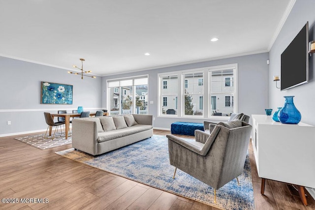 living room with ornamental molding, a chandelier, baseboards, and wood finished floors