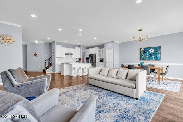 living area featuring light wood-type flooring, baseboards, a chandelier, and recessed lighting