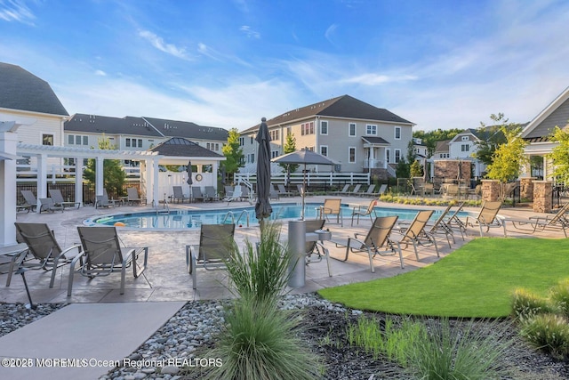 community pool with a patio area, fence, and a residential view