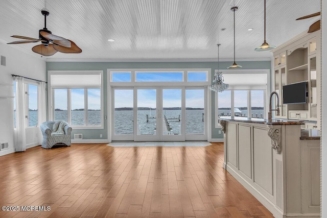 sunroom with visible vents, a water view, and ceiling fan