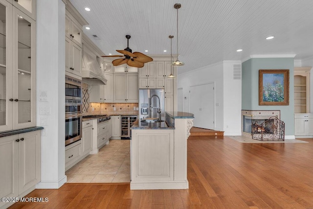 kitchen with light wood finished floors, beverage cooler, ornamental molding, stainless steel appliances, and a sink