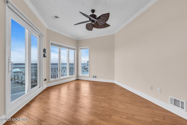 spare room with light wood finished floors, visible vents, and crown molding