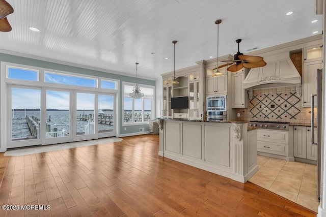 kitchen with custom exhaust hood, light wood-style flooring, decorative backsplash, appliances with stainless steel finishes, and glass insert cabinets