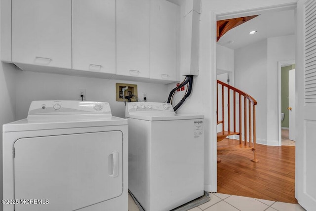 laundry area with light tile patterned floors, independent washer and dryer, and cabinet space