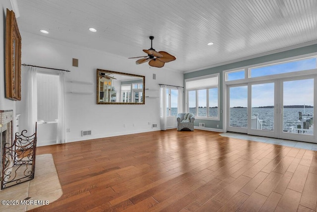 unfurnished living room with a fireplace, crown molding, visible vents, wood finished floors, and baseboards