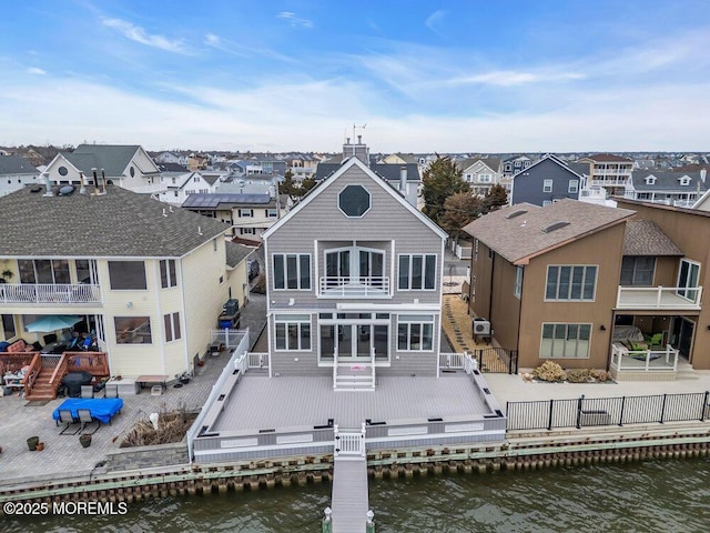 rear view of property featuring a balcony, a fenced backyard, a residential view, and a deck with water view