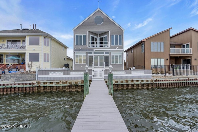 back of house featuring a sunroom, a deck with water view, and a balcony