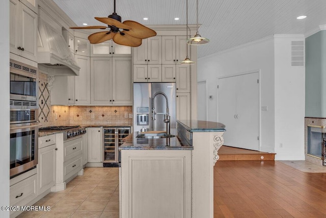 kitchen featuring wine cooler, crown molding, stainless steel appliances, tasteful backsplash, and premium range hood