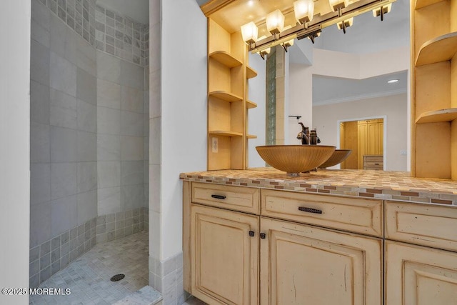 full bath featuring ornamental molding, tiled shower, and vanity