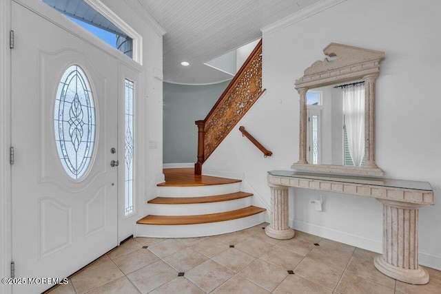 entryway with crown molding, stairway, a wealth of natural light, and light tile patterned flooring