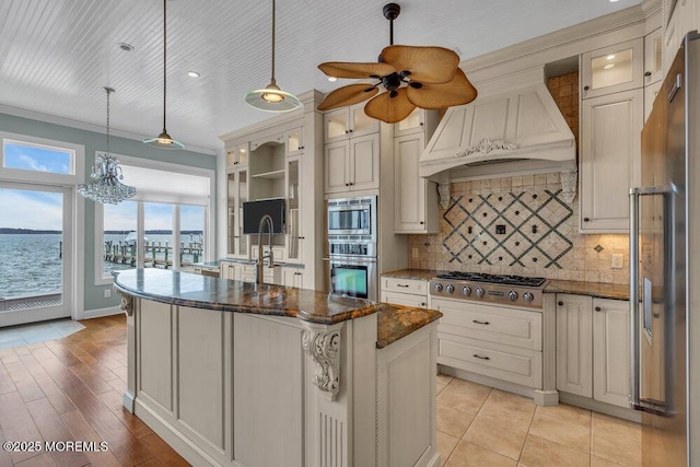 kitchen featuring decorative backsplash, a kitchen island, glass insert cabinets, appliances with stainless steel finishes, and custom exhaust hood