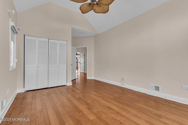 unfurnished bedroom with light wood-type flooring, visible vents, lofted ceiling, and baseboards