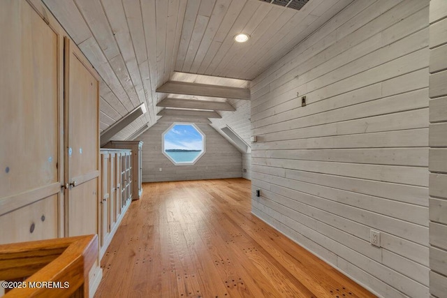 additional living space with lofted ceiling with beams, wooden ceiling, wooden walls, and light wood finished floors