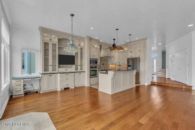 kitchen with ornamental molding, appliances with stainless steel finishes, a wealth of natural light, and light wood-style flooring