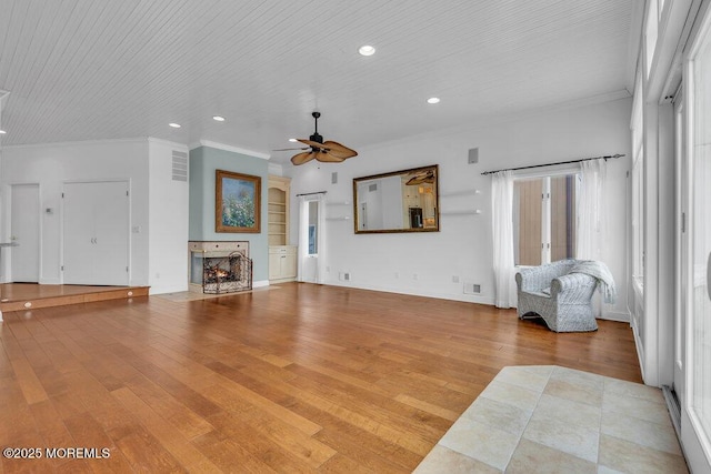 living room featuring a warm lit fireplace, wood finished floors, and crown molding