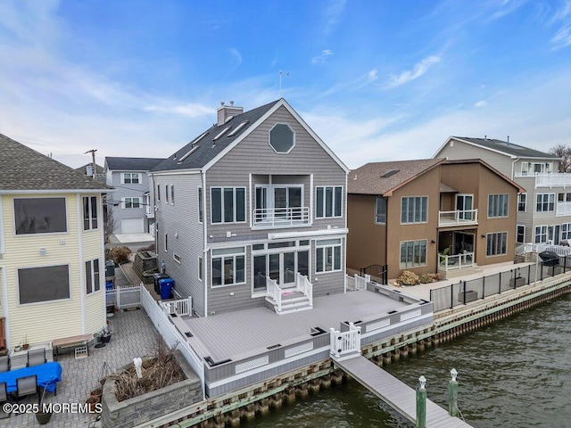 back of house featuring a balcony, a fenced backyard, a chimney, and a deck with water view