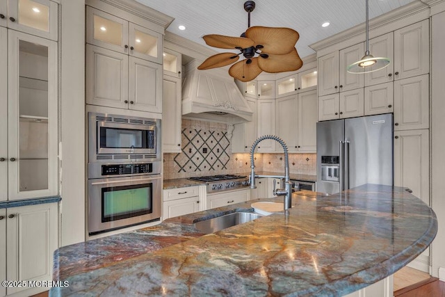 kitchen featuring stainless steel appliances, a sink, backsplash, custom exhaust hood, and pendant lighting